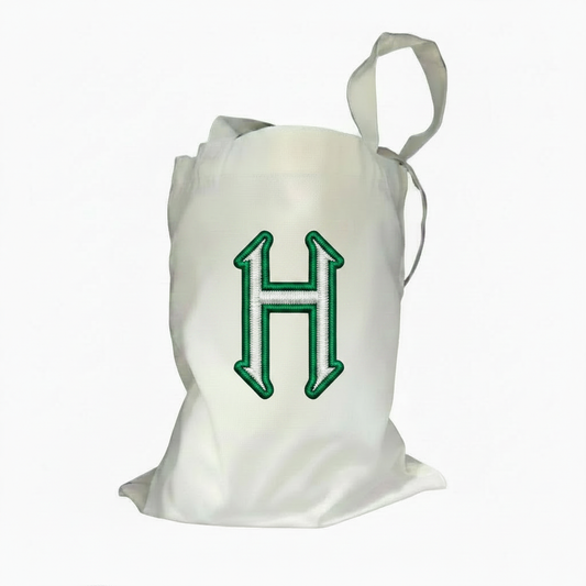 Natural canvas tote bag with embroidered green and white H patch graphic centered on front
